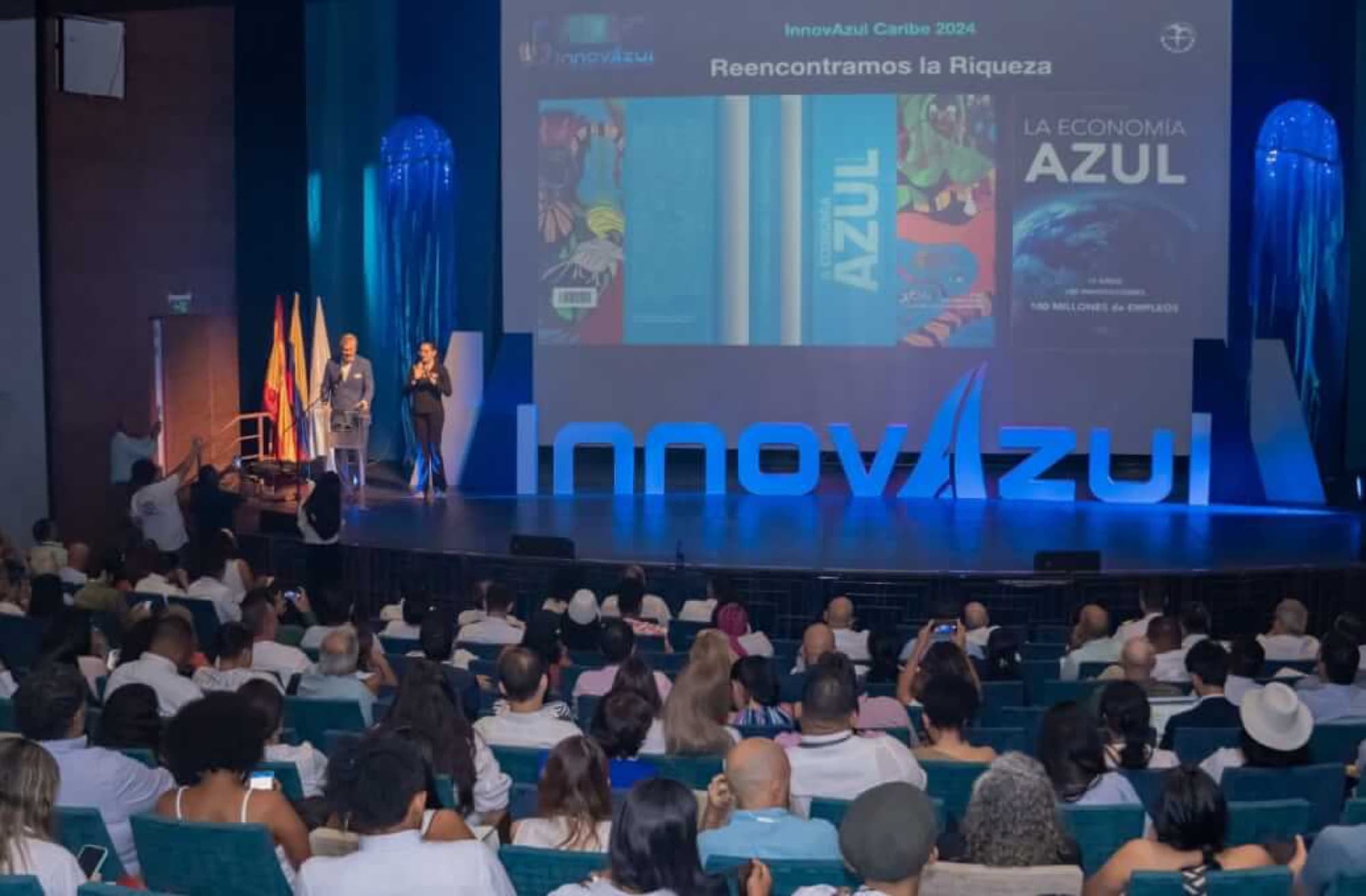 Apertura de InnovAzul Caribe 2024 ante un auditorio lleno, con el lema «Reencontramos la Riqueza» en pantalla.