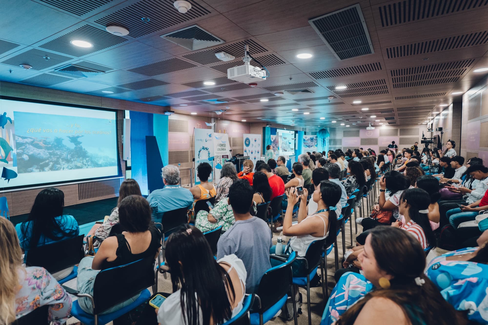 Asistentes siguiendo una charla sobre el cuidado de los océanos en el auditorio del evento.