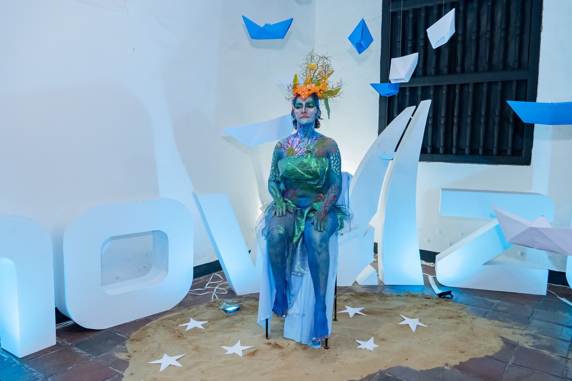 Performance de body paint inspirada en la vida marina junto a las letras de InnovAzul.